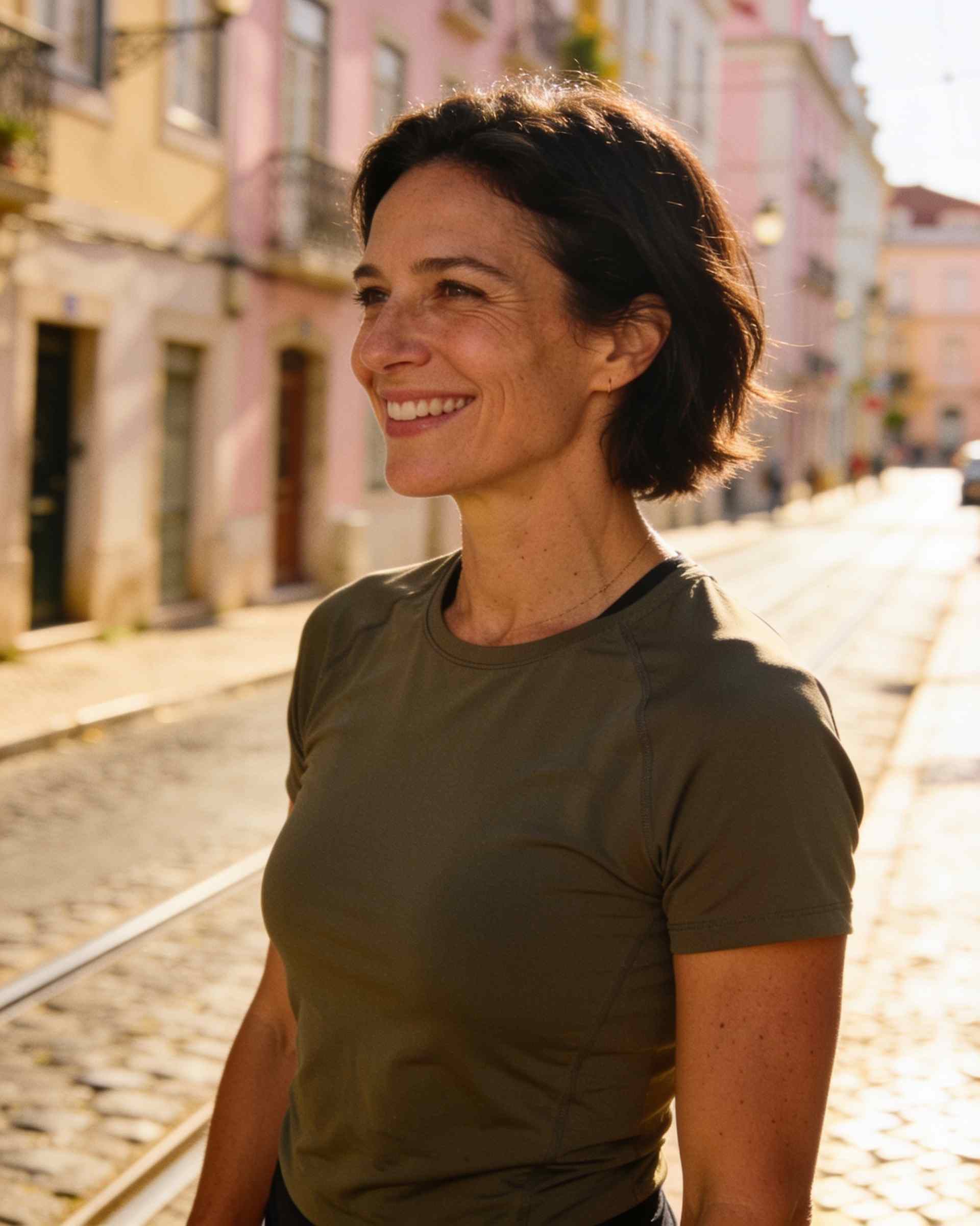 A woman in her forties in running kit, smiling, on a sunny city street